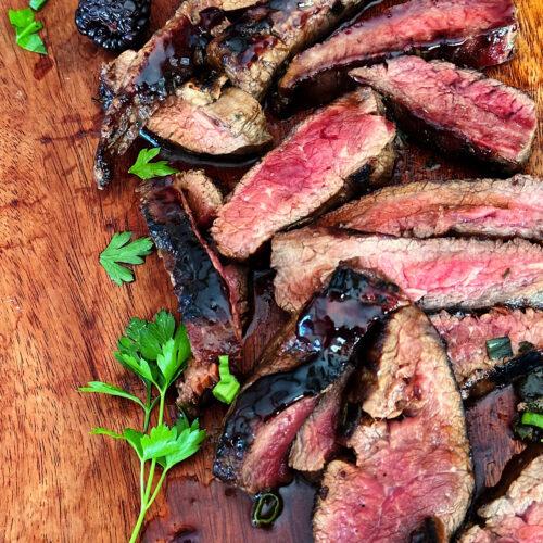 Sliced Flank steak with blackberry glaze on cutting board