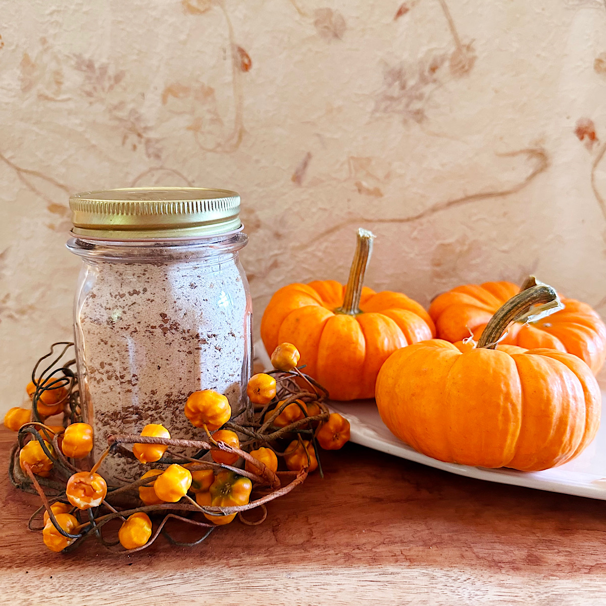 Pumpkin spice latte powdered dry mix in a jar with pumpkins behind it.