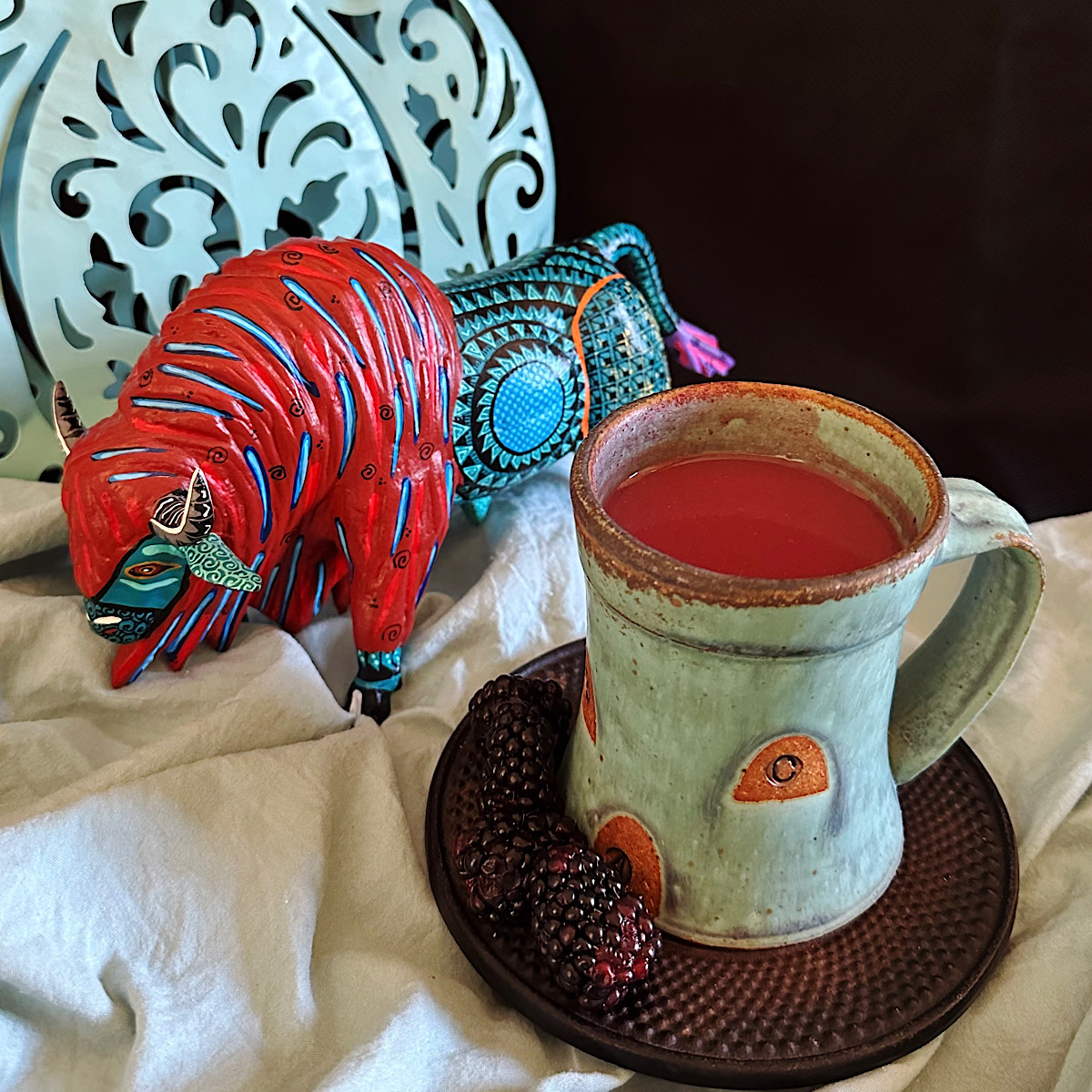 Blackberry atole drink with Mexican art objects behind it.