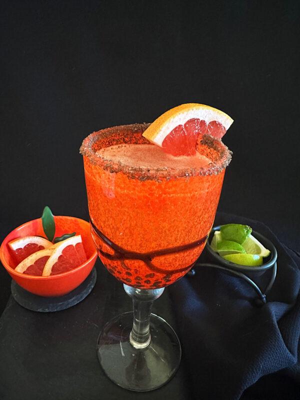 Paloma cocktail with sides of grapefruit and lime wedges.