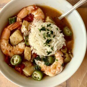 Louisiana seafood gumbo with okra and no file powder, served in in a white bowl with a mound of rice.