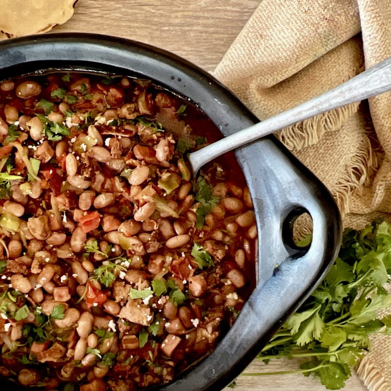 Tuscan white bean stew in black pot with side of parsley
