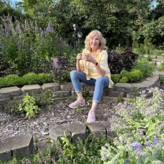 Dorothy Stainbrook in the herb garden with a cup of wellness tea
