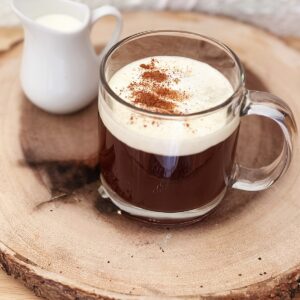 Tea latte on a round of wood with side of creamer