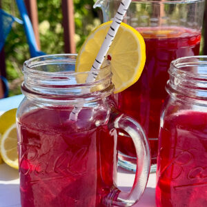 Hibiscus tea made with looseleaf tea from HeathGlen in glass with lemon garnish on the deck in summer.