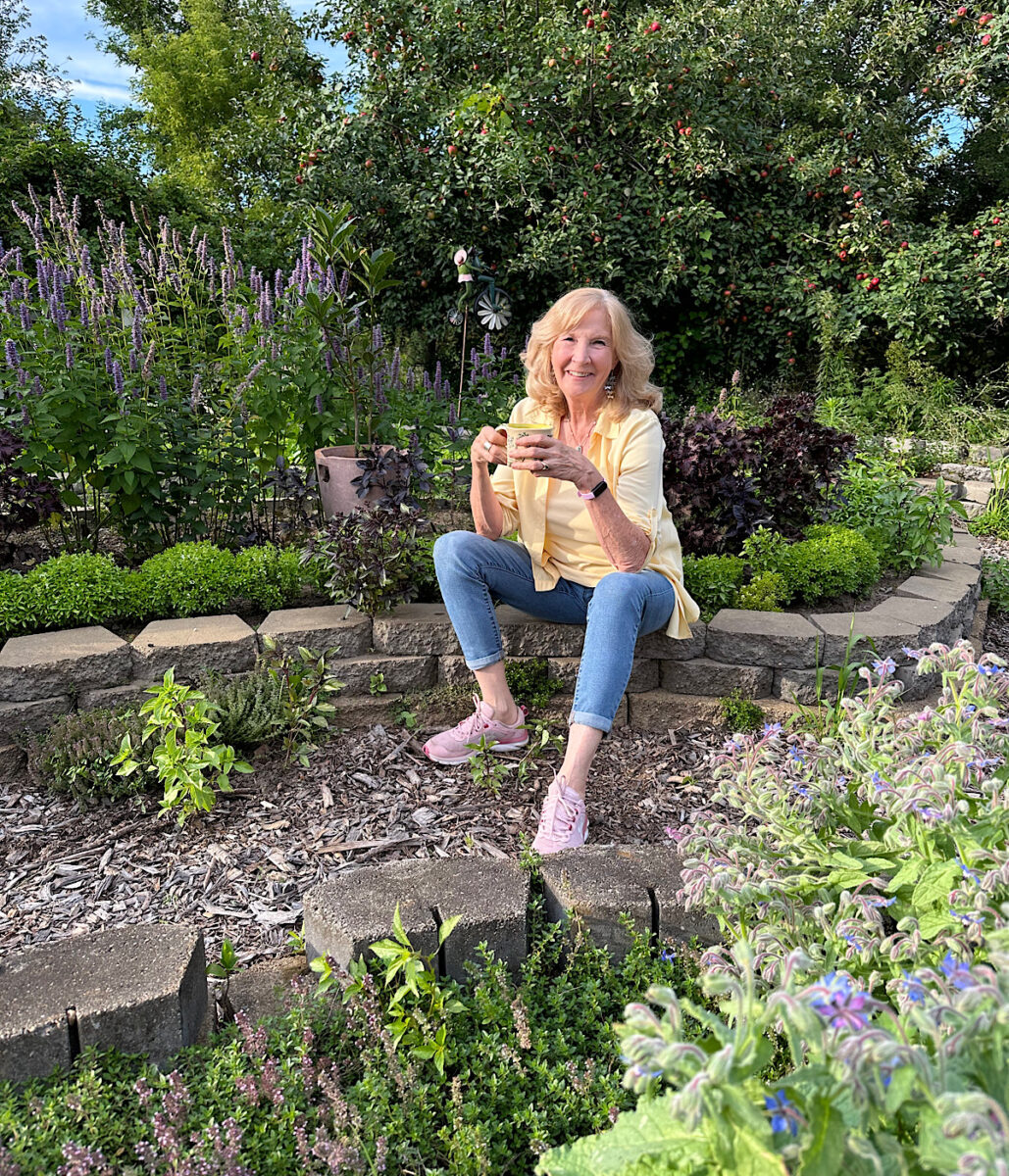 Dorothy in herb garden with a cup of herbal tea.