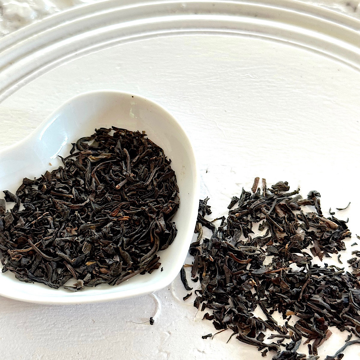 Lapsang Souchong (Brewers Build) looseleaf tea from HeathGlen Farm on a white plate and in a heart-shaped dish.