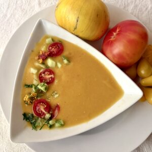 Yellow heirloom tomato gazpacho using heirloom tomatoes from HeathGlen Farm. Includes varieties called Pork Chop, Oaxaca Gold, and Yellow Pear. Garnished with red cherry tomatoes, chopped cucumbers and cilantro.