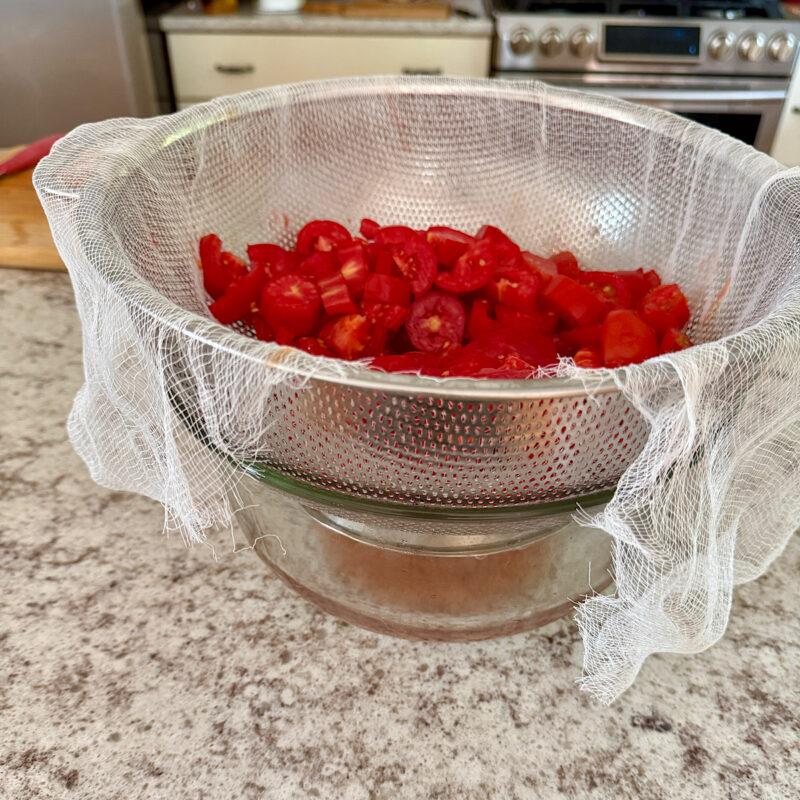 Fresh heirloom tomatoes from HeathGlen Farm chopped and put in colander with cheesecloth over a bowl to make tomato water.