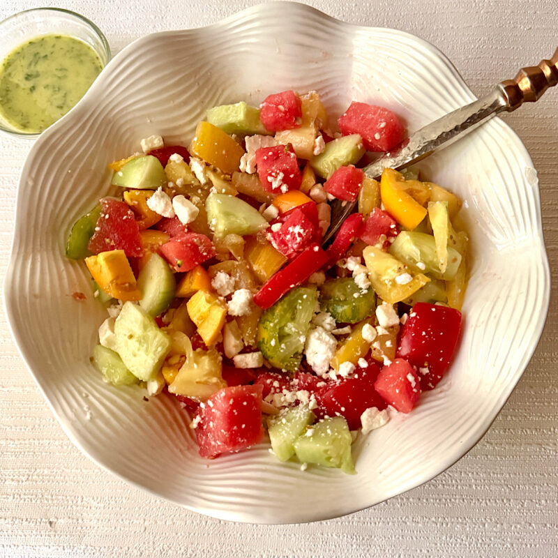 Finished watermelon tomato salad with watermelon, heirloom tomatoes, cucumber, feta cheese, lemon verbena dressing and pistachios.