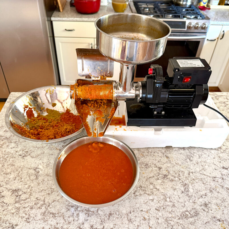 Commercial electric food mill making heirloom tomato freezer sauces.